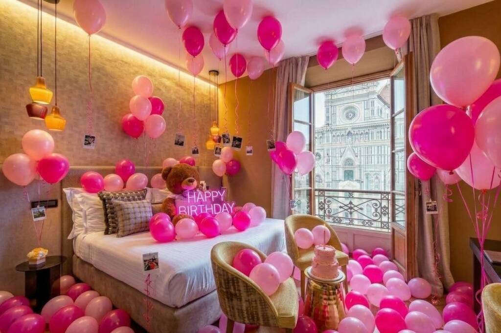 Hotel room decorated in pink and fuchsia balloons for a birthday, with a window facing Florence Cathedral